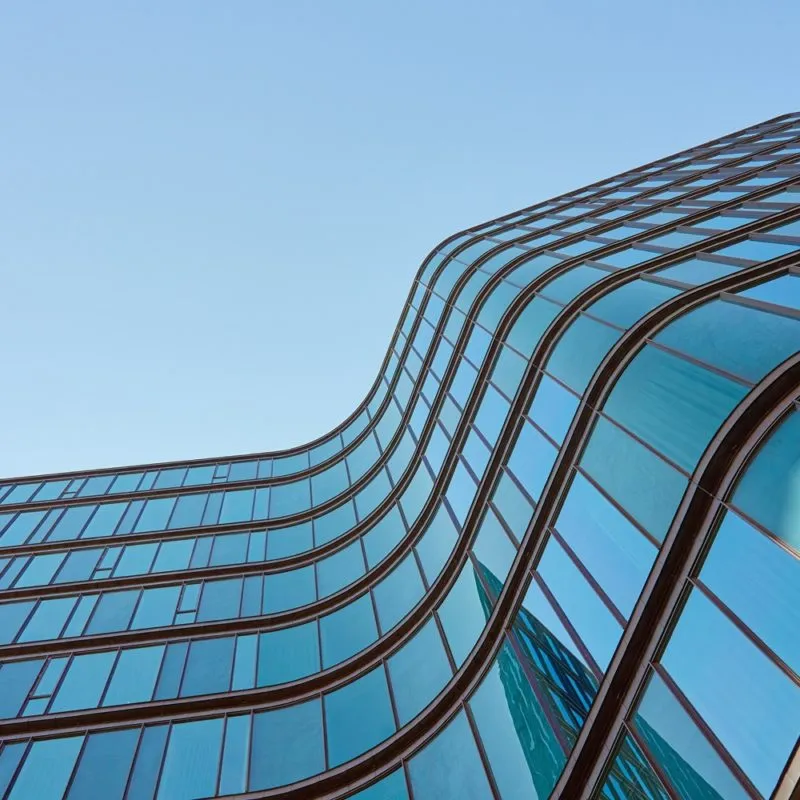 Modern,Building,With,Curved,Glass,Facade,Reflecting,Sky ,Contemporary,Architectural